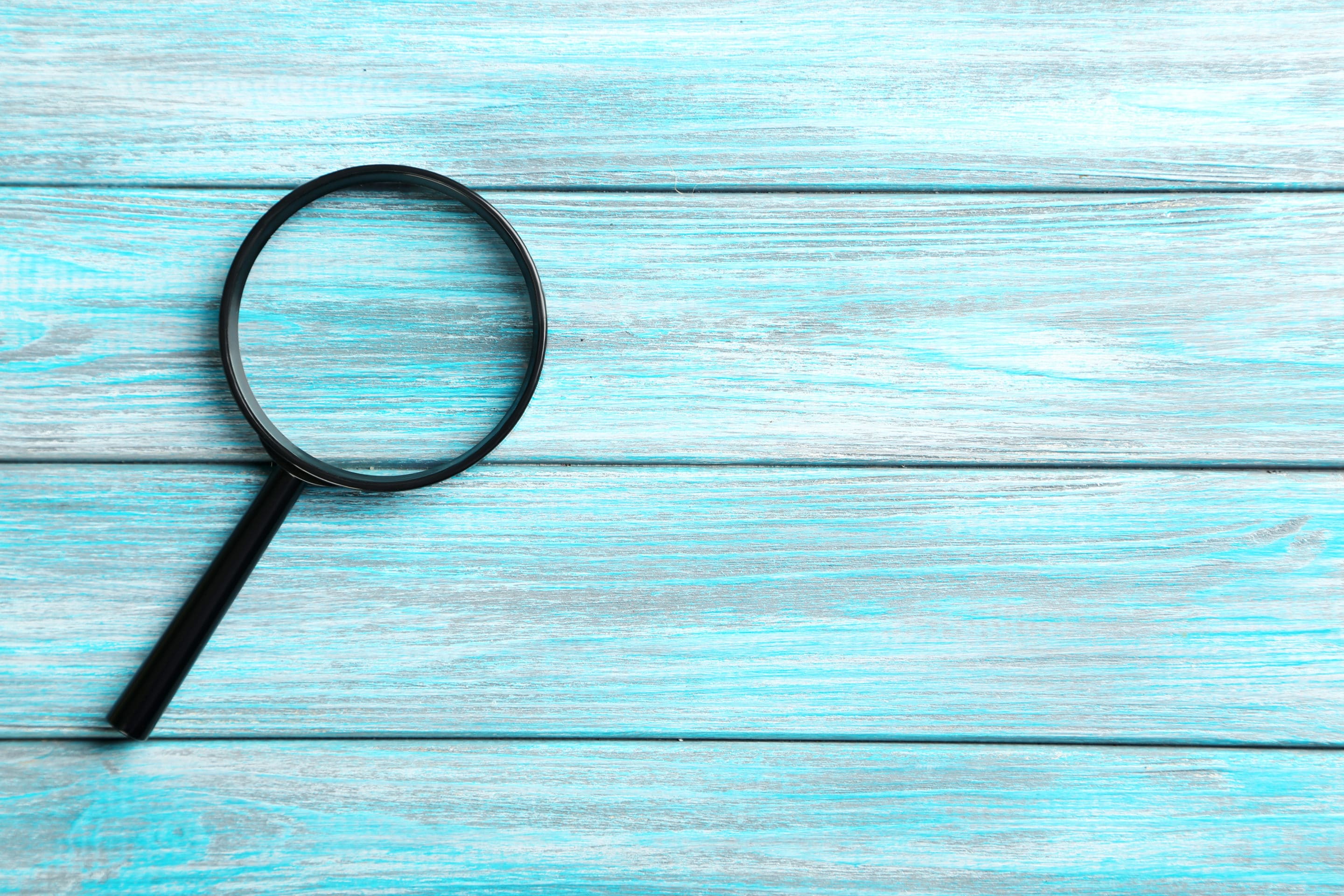 Magnifying glass on a blue wooden table institut d'études marketing
